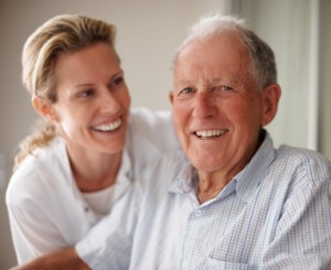 Closeup portrait of a happy senior man on a wheel chair with a nurse for assistance